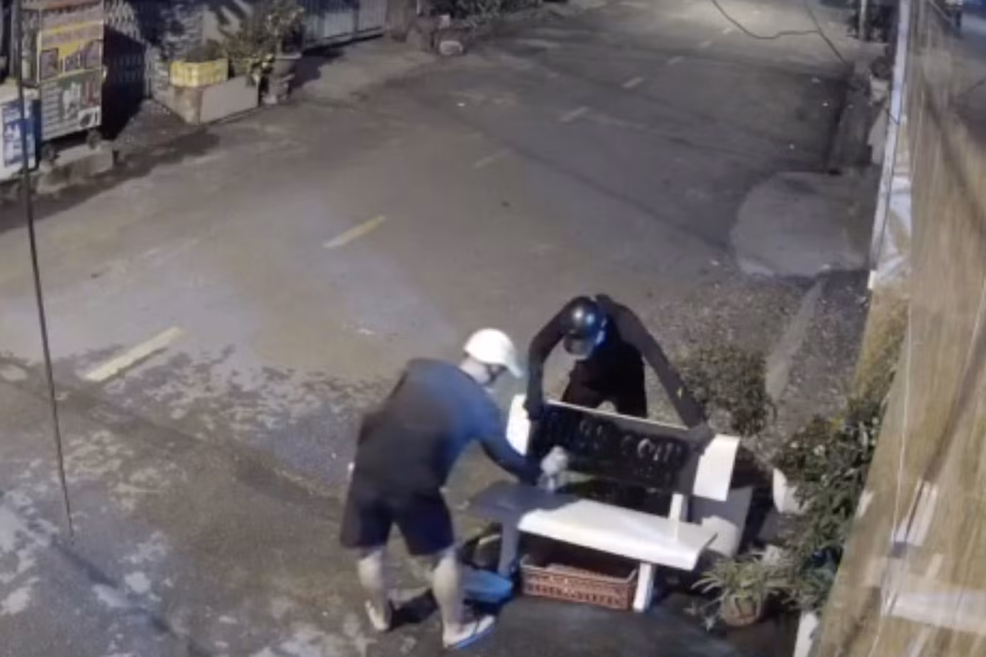 Hai thanh niên xịt sơn đen, in trang web cá độ lên ghế đá trước nhà dân (Ảnh cắt từ clip). Hai thanh niên xịt sơn đen, in trang web cá độ lên ghế đá trước nhà dân (Ảnh cắt từ clip).