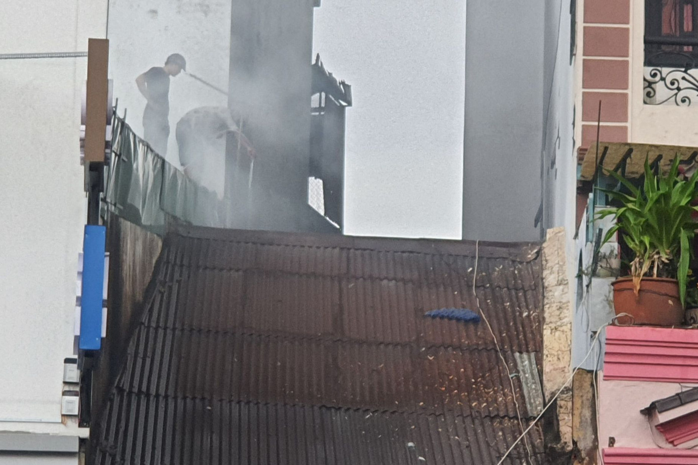 Người dân leo mái nhà hàng xóm để xịt nước chữa cháy (Ảnh: Hoàng Thuận).