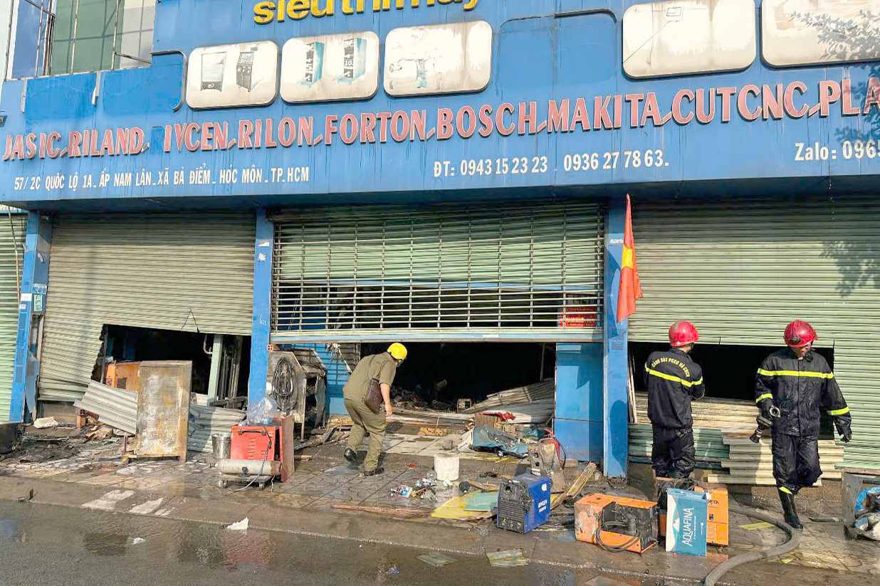 Lực lượng chữa cháy cắt cửa cuốn để dập lửa. Ảnh: C.A.