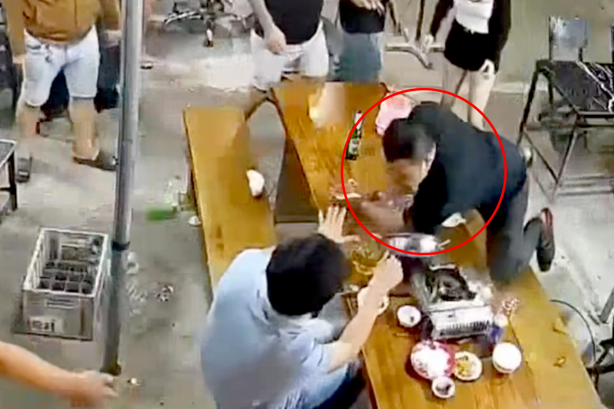 Camera ghi cảnh ông Vĩ chồm lên bàn để tấn công ông T.. Ảnh cắt từ clip.