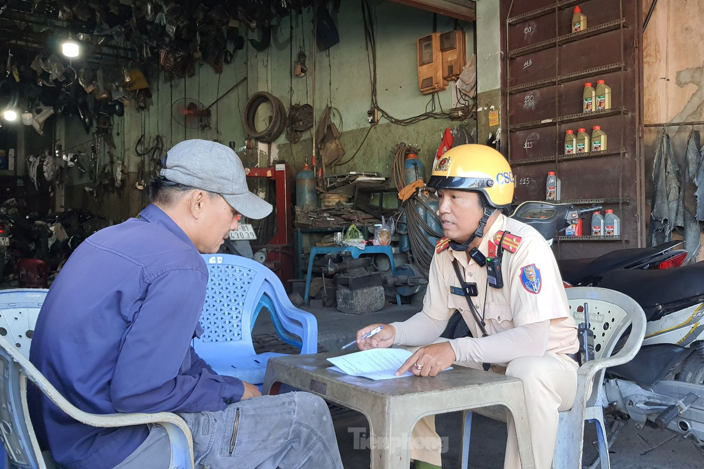 CSGT vận động chủ tiệm sửa xe trên quốc lộ 1 ký cam kết không rải đinh nhọn. Ảnh: Hoàng Thuận.