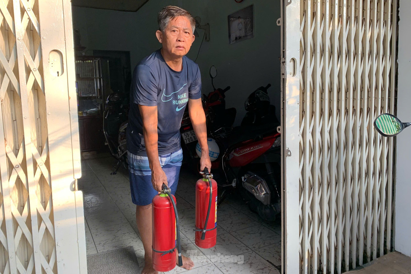 Ông Hùng cầm 2 bình chữa cháy sang hỗ trợ dập lửa. Ảnh: Hoàng Thuận. Ông Hùng cầm 2 bình chữa cháy sang hỗ trợ dập lửa. Ảnh: Hoàng Thuận.