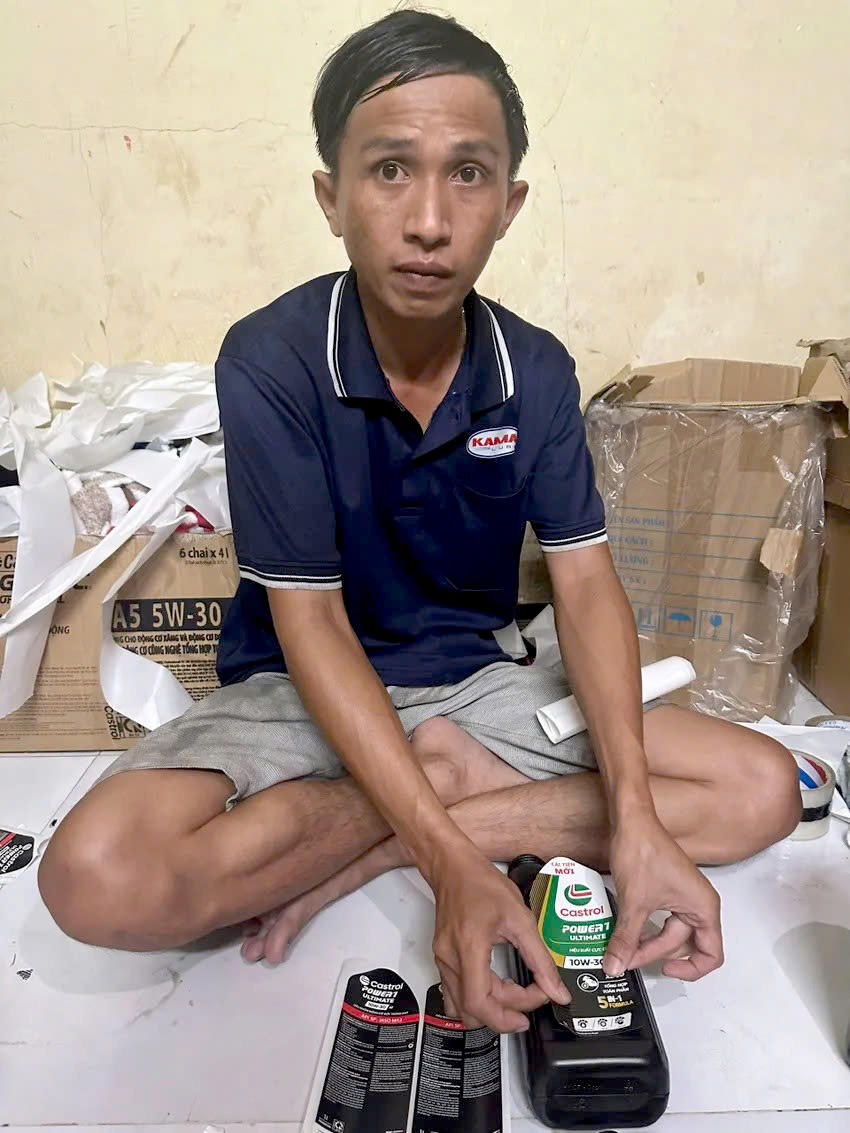 Nguyễn Văn Khánh thực hiện lại hành vi dán tem nhãn lên các chai nhớt giả. Ảnh: C.A.