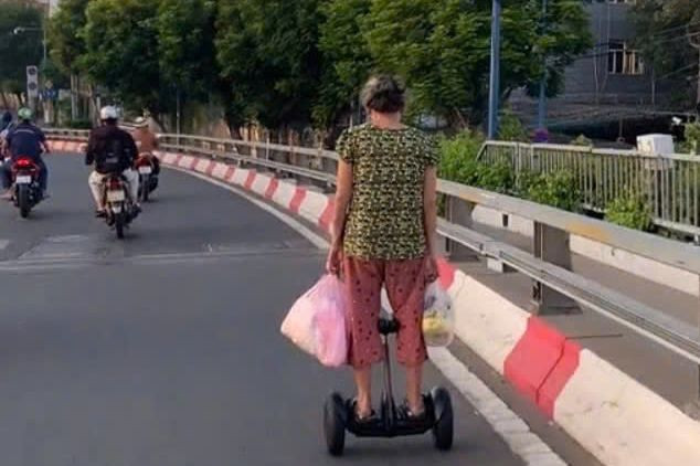 Hình ảnh bà M. đi xe điện cân bằng trên cầu Khánh Hội. Ảnh cắt từ clip. Hình ảnh bà M. đi xe điện cân bằng trên cầu Khánh Hội. Ảnh cắt từ clip.