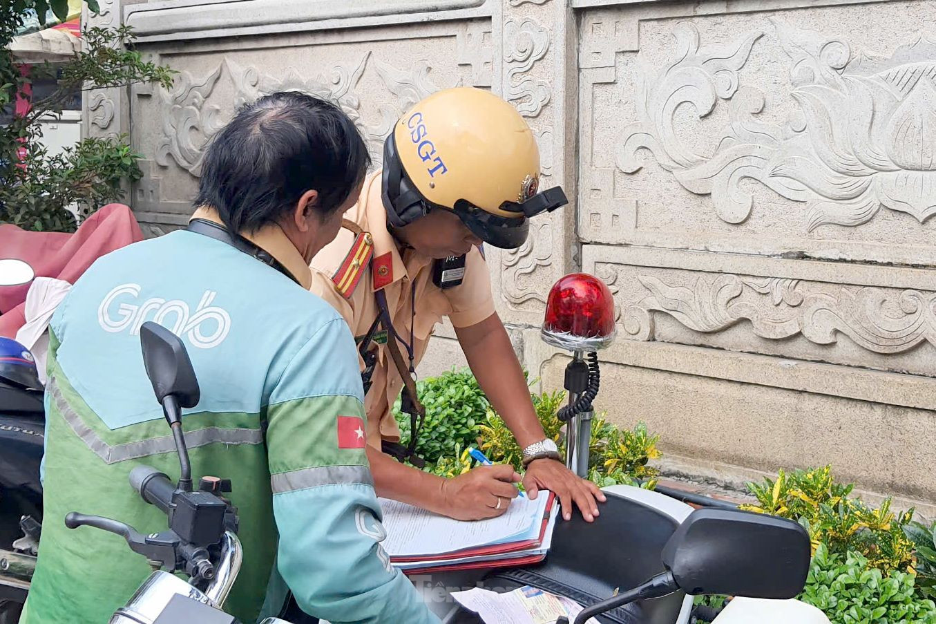 CSGT lập biên bản xử phạt đối với ông C. về lỗi đi xe máy trên vỉa hè. Ảnh: Hoàng Thuận.