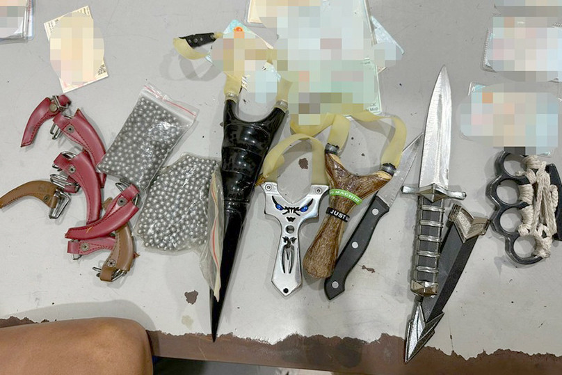 Dao, ná và bi sắt tìm thấy trong cốp xe máy của nhóm thanh niên. Ảnh: A.X. Dao, ná và bi sắt tìm thấy trong cốp xe máy của nhóm thanh niên. Ảnh: A.X.