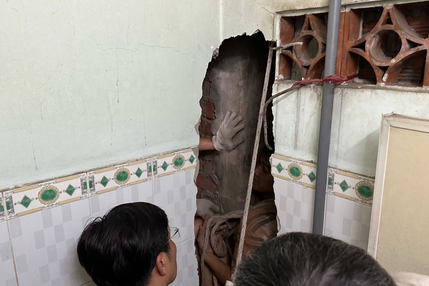 Lực lượng chức năng đục một phần bức tường của căn nhà để đưa nam thanh niên ra ngoài. Ảnh: M.A.