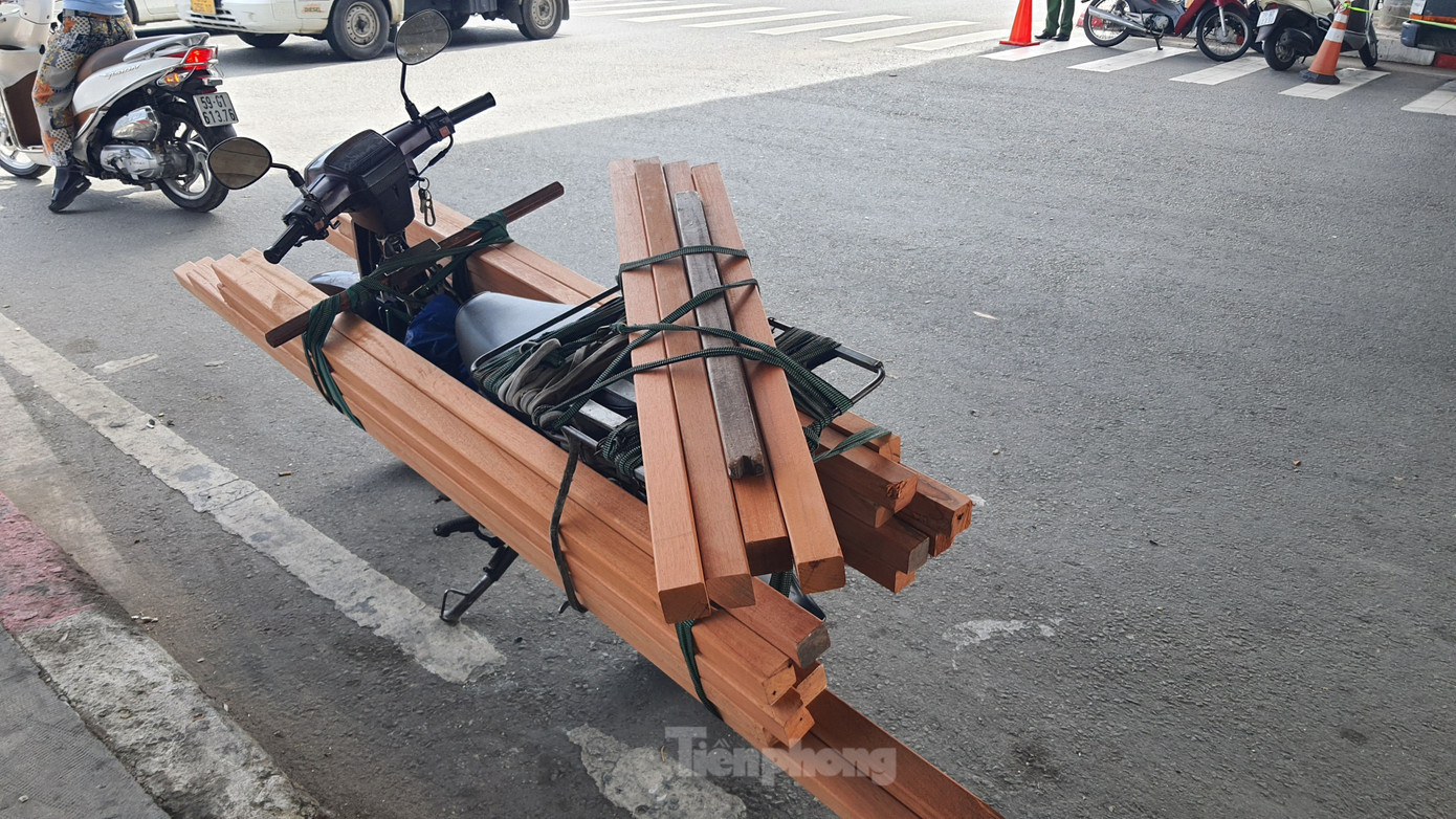 Ông T. chất đầy thanh gỗ dài cặp bên hông xe để giao cho khách. Ảnh: Hoàng Thuận. Ông T. chất đầy thanh gỗ dài cặp bên hông xe để giao cho khách. Ảnh: Hoàng Thuận.