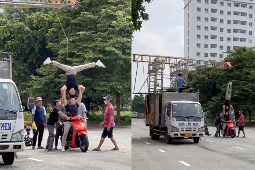 Hai nghệ sĩ thực hiện động tác chồng đầu lên nhau có sự hỗ trợ, giám sát của nhiều người. Ảnh cắt từ clip.