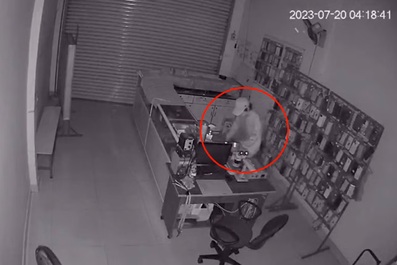 Người đàn ông lục lọi lấy tài sản trong cửa hàng điện thoại (Ảnh cắt từ clip).