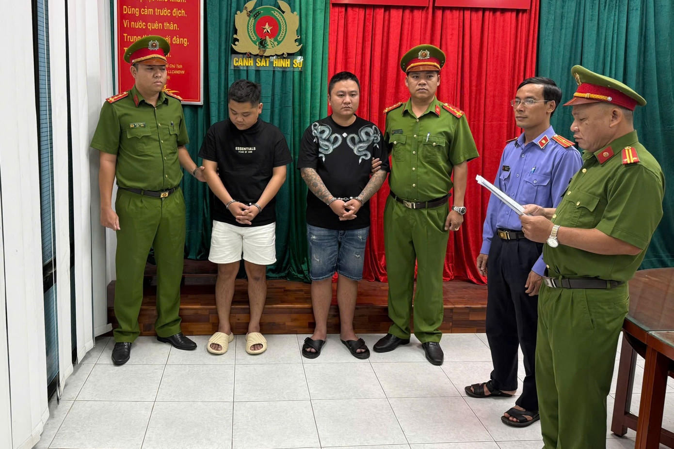 Cơ quan công an tống đạt các quyết định Hảo (quần trắng) và Tú. Ảnh: Công an cung cấp.