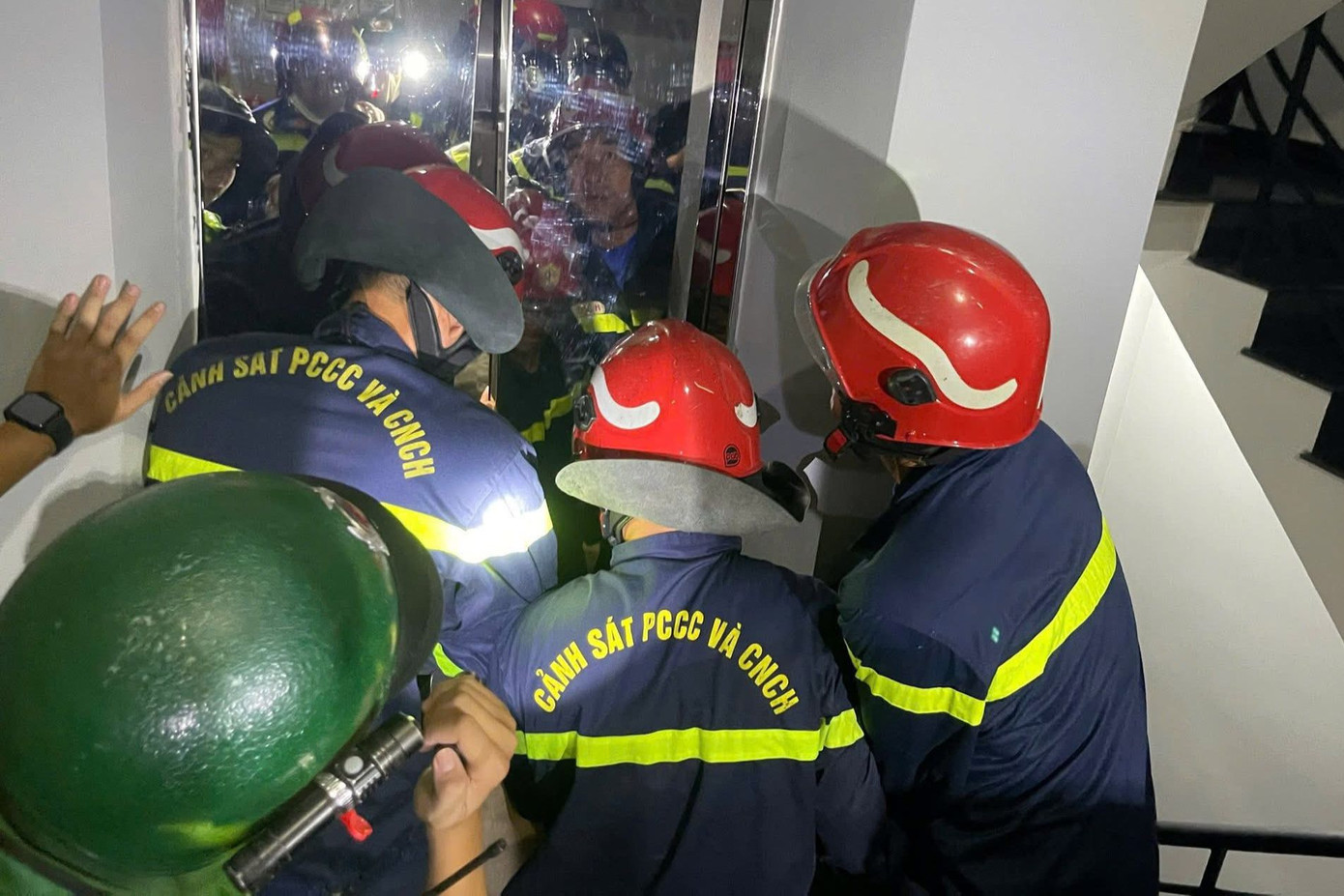 Lực lượng chức năng dùng thiết bị chuyên dụng mở cửa thang máy để đưa cô gái ra ngoài. Ảnh: C.A.