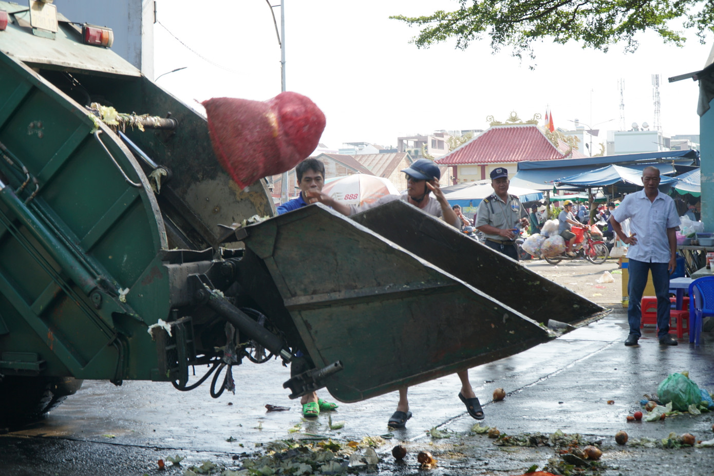 Tiểu thương Trương Văn Tùng (đội mũ bảo hiểm màu đen) chủ động mang rác đến bỏ tại Trạm xử lý rác thải.
