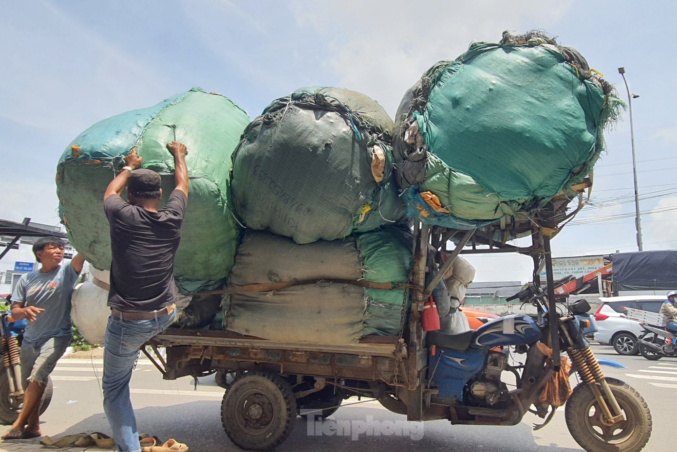 Ông Đ. (áo đen) tháo dỡ hàng hóa để lực lượng chức năng tạm giữ xe ba gác. Ảnh: Hoàng Thuận.