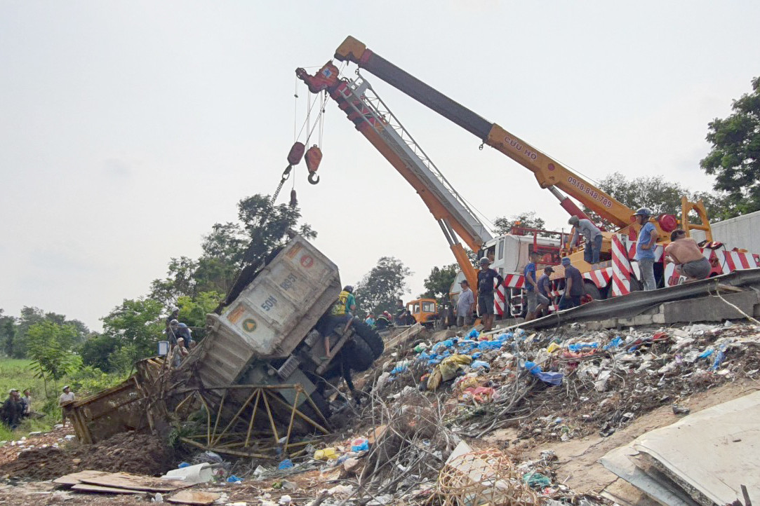 Xe ben lao xuống vệ đường được khung cần cẩu giữ lại. Ảnh: Minh Anh.