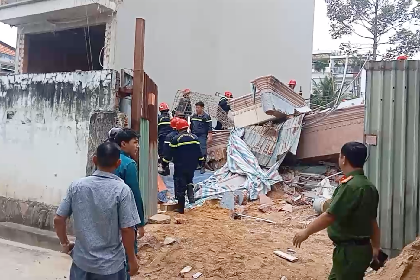 Gạch đá, vật liệu xây dựng ngổn ngang. Xe cứu thương và nhân viên y tế cũng có mặt tại hiện trường để cấp cứu người bị nạn.