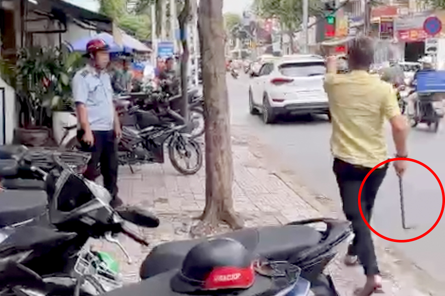 Ông H cầm xà beng (khoanh tròn đỏ) đuổi, dọa đánh cán bộ trật tự đô thị (Ảnh cắt từ clip).