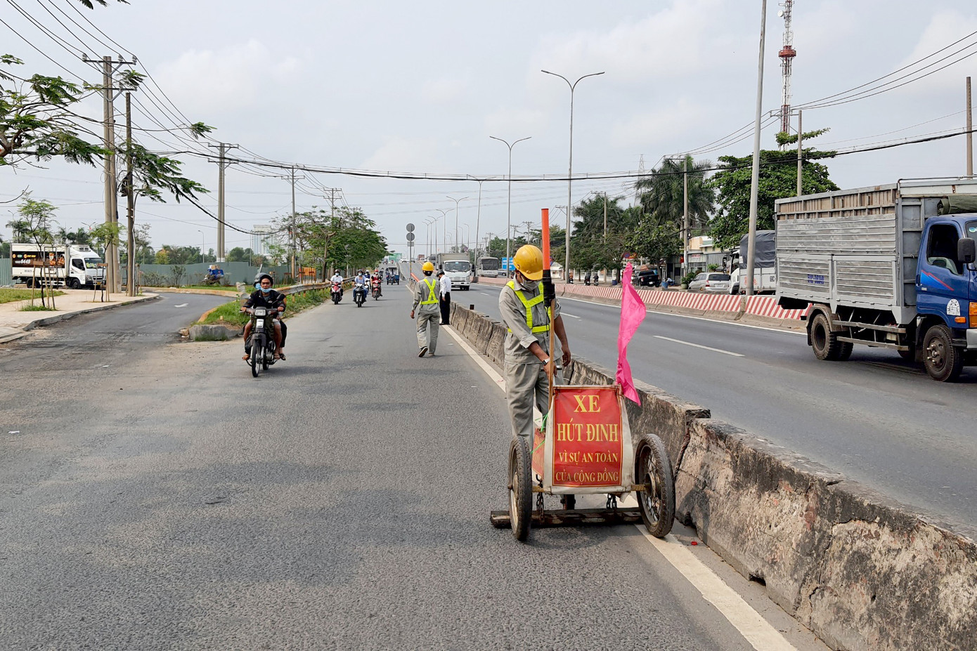 Nhân viên của Công ty cổ phần đầu tư và phát triển hạ tầng IDICO kéo xe tự chế đi hút đinh để an toàn cho người đi đường. Ảnh: Minh Anh.