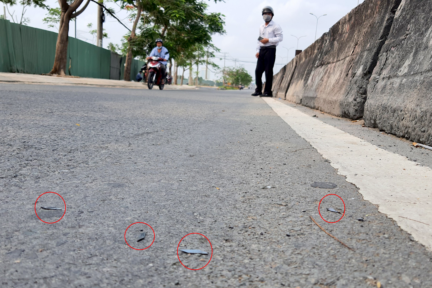 Các mảnh đinh nằm sát dải phân cách chờ găm vào bánh xe máy. Ảnh: Minh Anh.