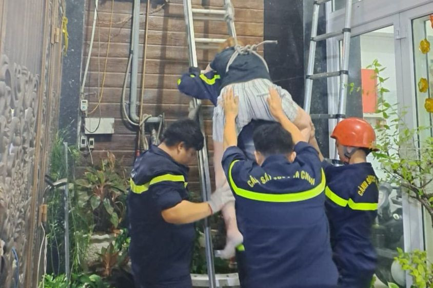 Lực lượng cứu hộ dùng thang tiếp cận và cõng nạn nhân xuống đất. Ảnh: Tấn Tài.