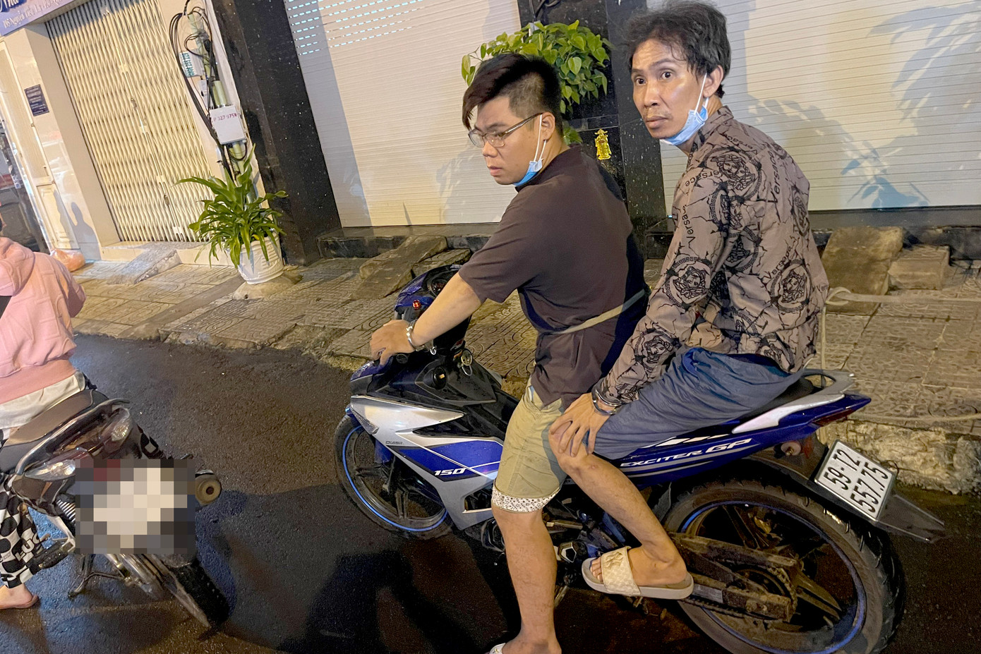 Tài (đeo kính) và Dũng thực hiện lại hành vi giật túi xách của chị N. (Ảnh: Hoàng Thuận).