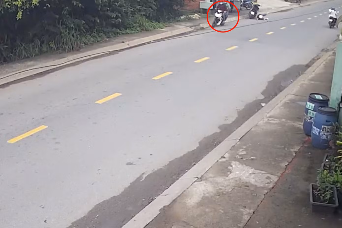 Chị P ngã từ trên xe máy xuống đường sau cú giật của hai thanh niên trong khoanh tròn đỏ (Ảnh cắt từ clip). Chị P ngã từ trên xe máy xuống đường sau cú giật của hai thanh niên trong khoanh tròn đỏ (Ảnh cắt từ clip).