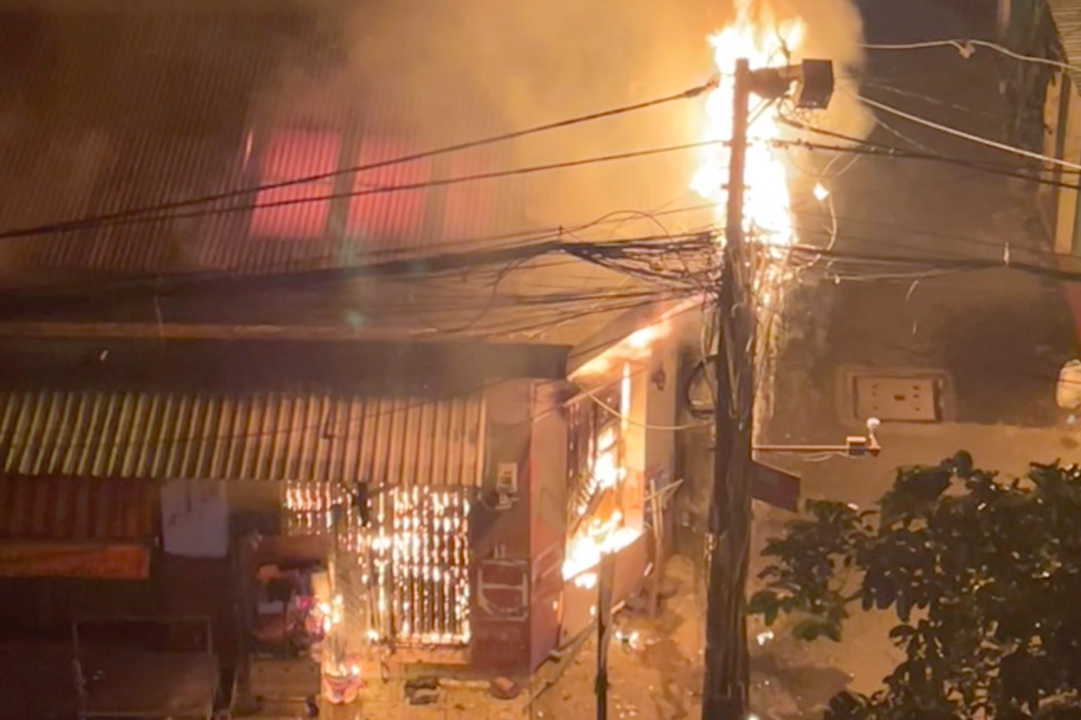 Lửa bao trùm căn nhà rồi cháy lan sang cột điện. Ảnh: H.T. Lửa bao trùm căn nhà rồi cháy lan sang cột điện. Ảnh: H.T.