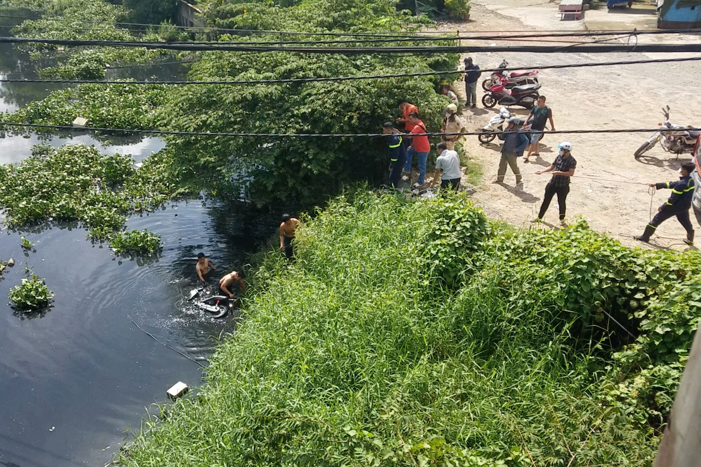 Lực lượng chức năng trục vớt xe máy lên bờ (Ảnh: H.T.).