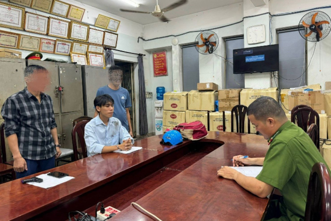 Cơ quan công an lấy lời khai đối với Nhữ Ngọc Long (áo sơ mi màu xanh) - kẻ dùng súng cướp tiệm vàng ở quận Tân Bình vào tháng 12/2023.