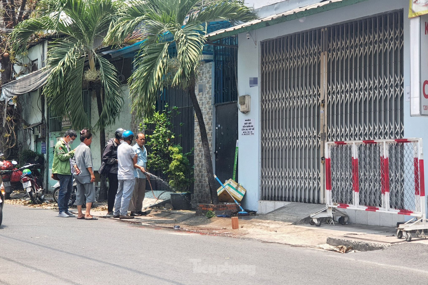 Người dân tẩy rửa vết máu trên mặt đường. Ảnh: Hoàng Thuận.