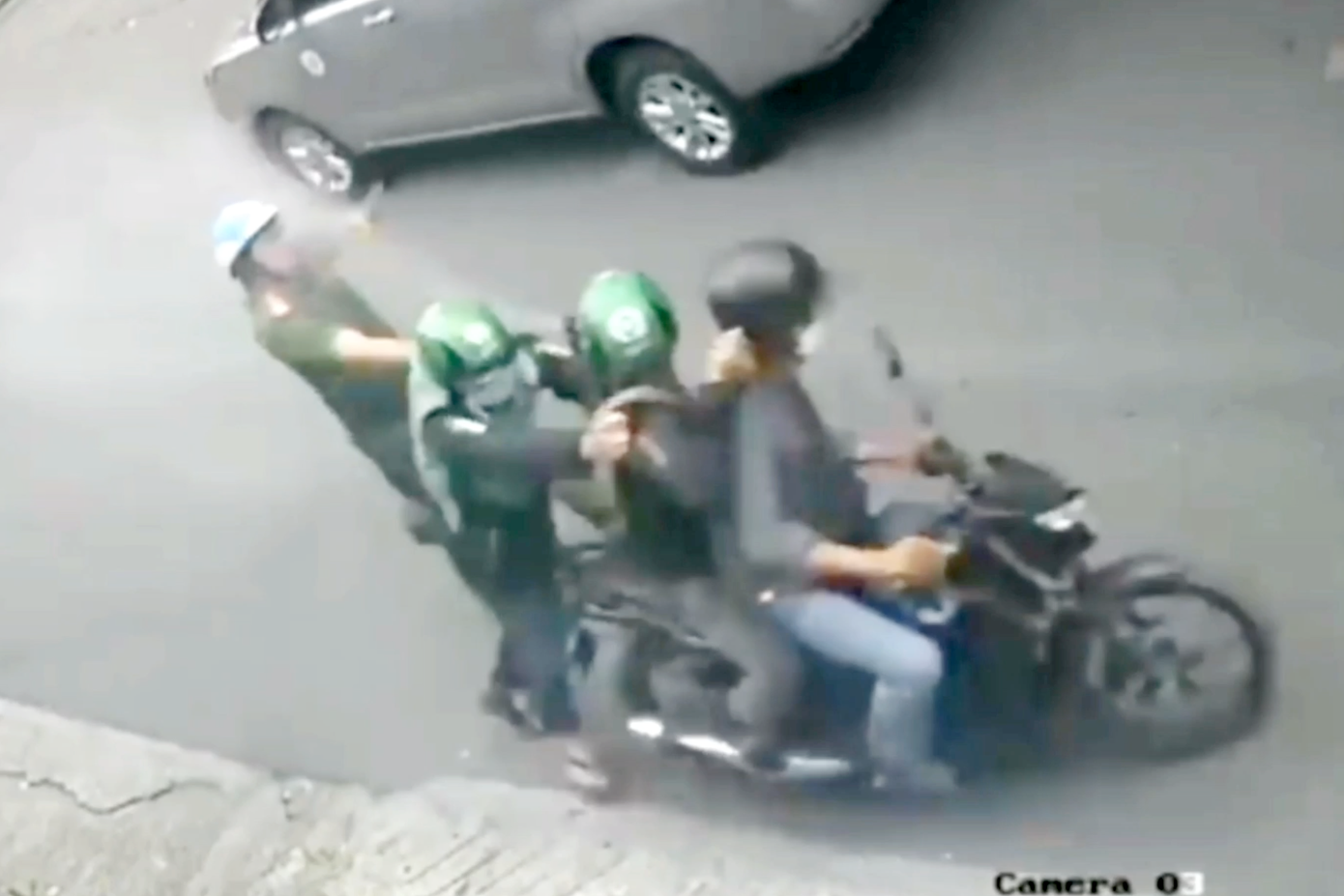Đối tượng ngồi sau xe máy xịt hơi cay vào mặt chiến sĩ công an để giải cứu đồng bọn (Ảnh cắt từ clip).