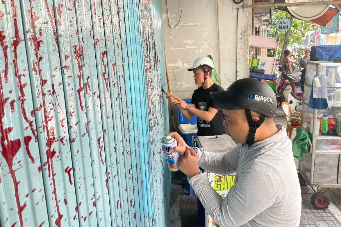 Hai nghi phạm tự nguyện cạo, sơn lại cửa cho bị hại. (Ảnh: Công an cung cấp).