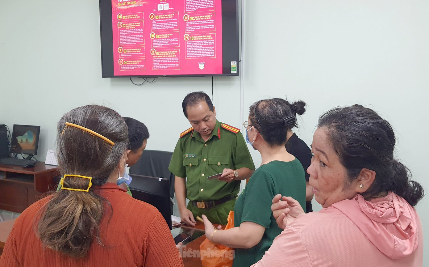 Cán bộ PC06 hướng dẫn người lớn tuổi làm thủ tục. Ảnh: Hoàng Thuận.