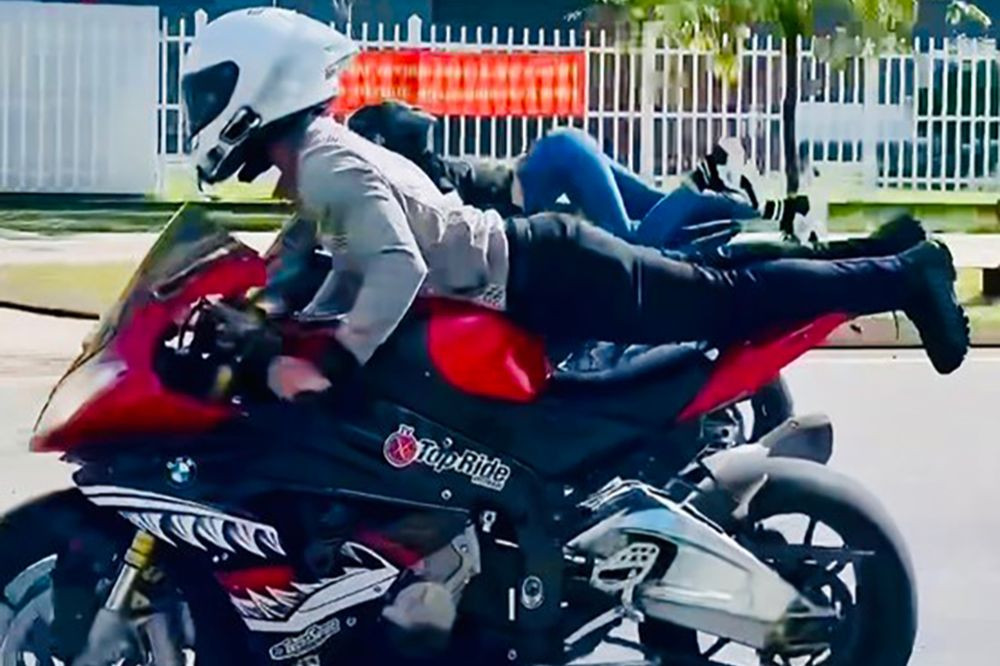 Ông Đông và người mẫu Ngọc Trinh nằm trên thân xe khi điều khiển mô tô. Ảnh cắt từ clip.