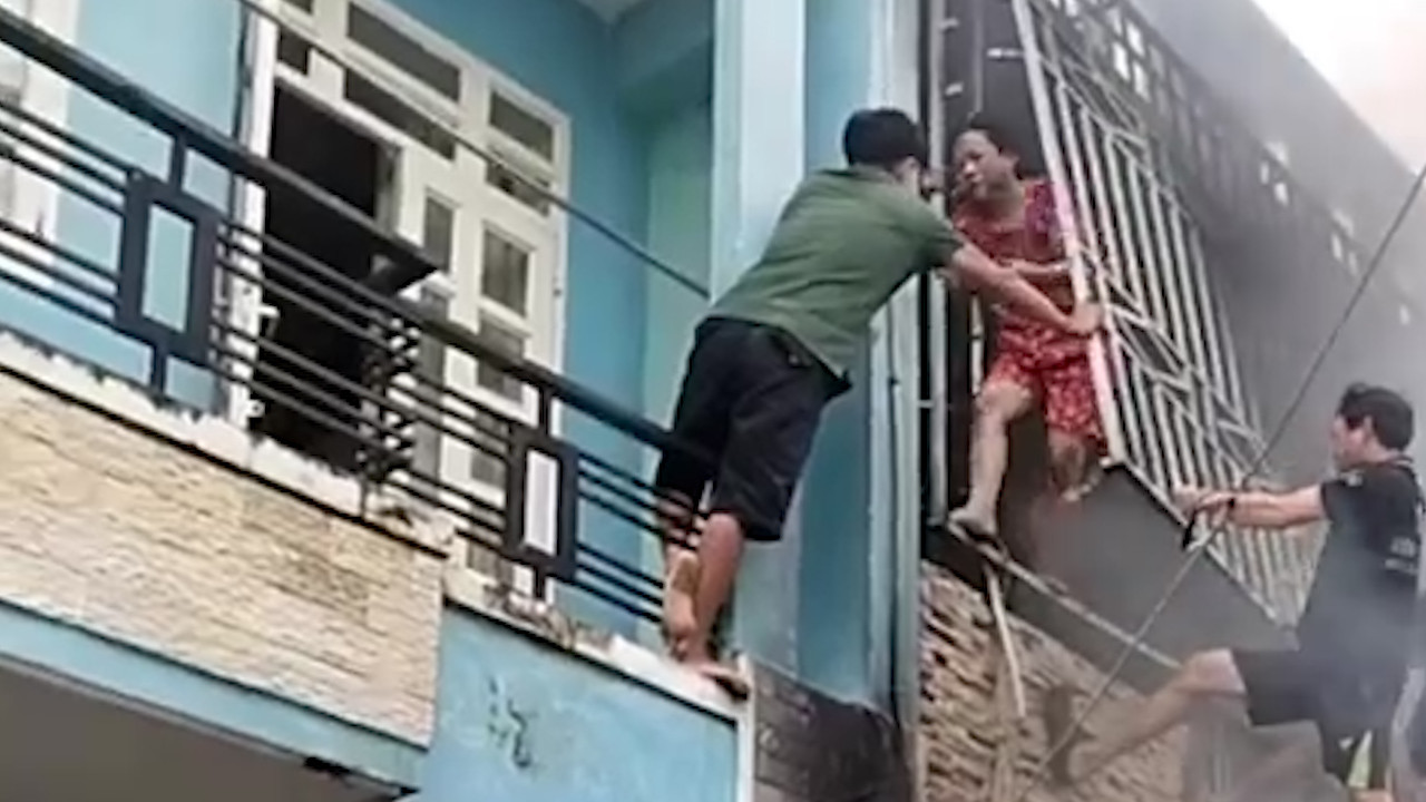 Người dân phá khung sắt cứu vợ chồng chủ nhà cùng con gái ra ngoài an toàn (Ảnh cắt từ clip).