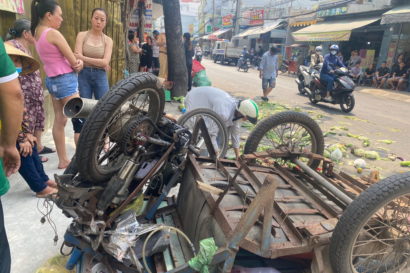 Xe ba gác bán rau củ bị tông lật úp, hàng hóa vương vãi khắp mặt đường. Ảnh: C.H.