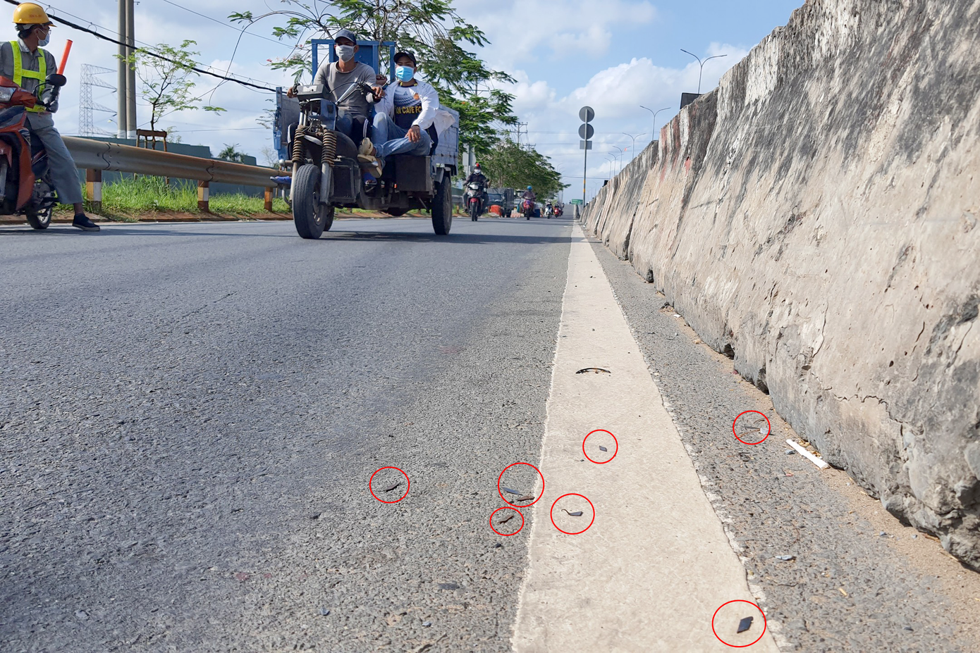 Các mảnh đinh trong khoanh tròn đỏ rải dày đặc trên quốc lộ 1. Ảnh: Minh Anh.