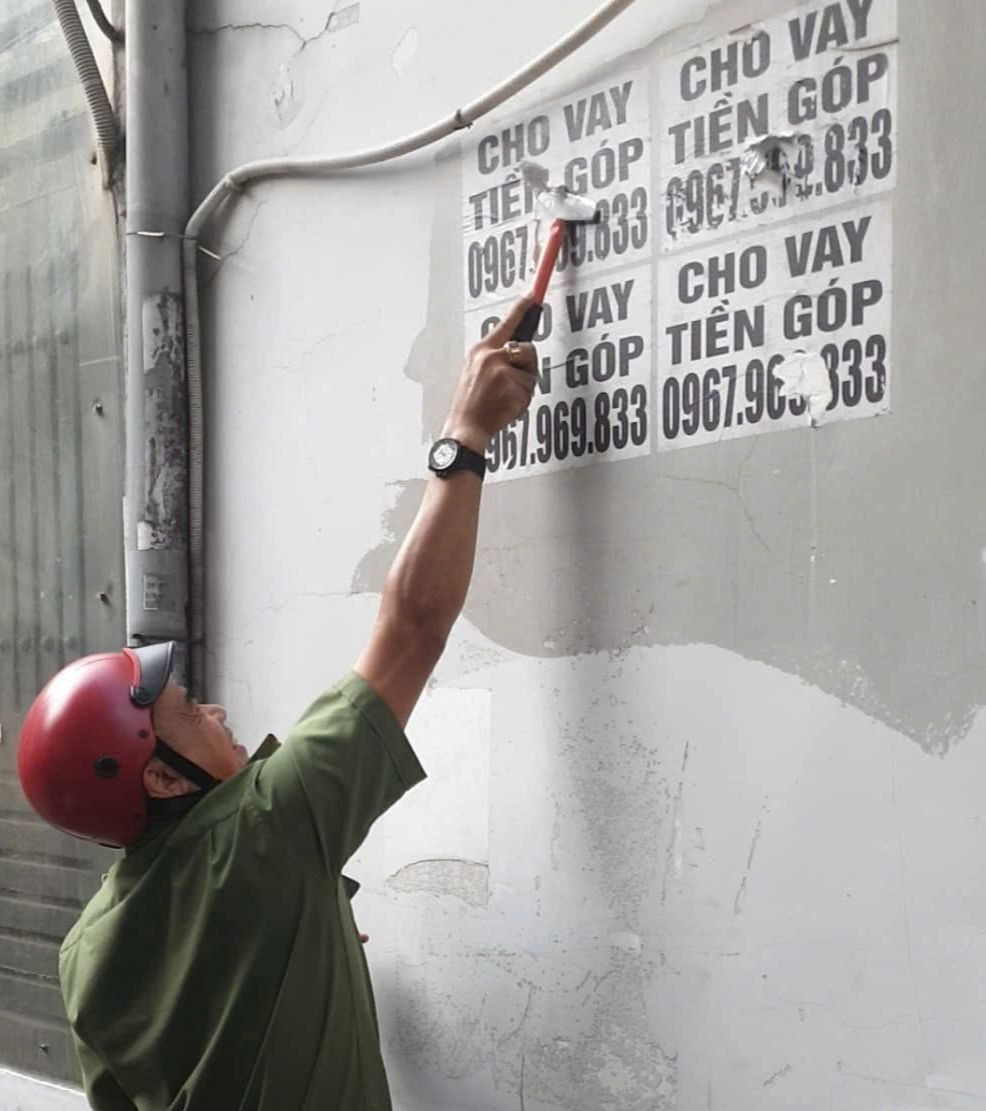 Lực lượng công an bóc xóa quảng cáo cho vay tiền dán trên tường. Ảnh: C.A.