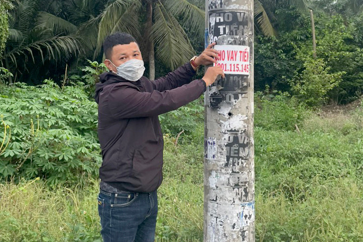 Công an đưa Trần Kim Tư đi bóc, gỡ các tờ rơi quảng cáo cho vay tiền đã dán trước đó.