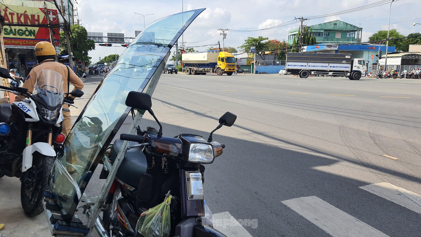 Ông V. dùng xe máy chở tấm kính có chiều cao 1,7m đi lắp đặt cho khách. Ảnh: Hoàng Thuận