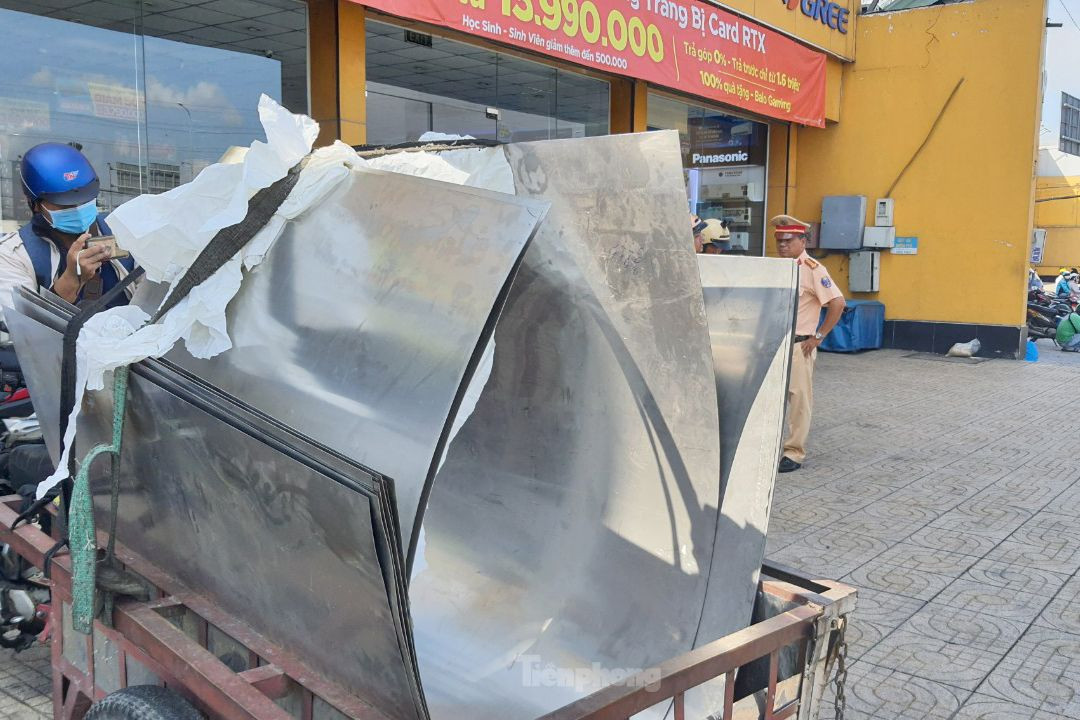 Ông P. chở nhiều tấm thép bằng xe máy gắn theo ba gác tự chế. Ảnh: Hoàng Thuận