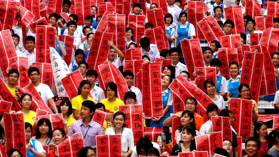 Người Malaysia gốc Hoa cùng giơ cao câu đối đỏ ngày Tết. Ảnh: BBC