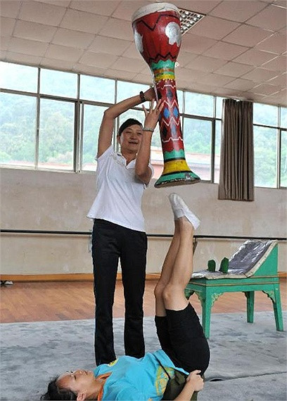 Giáo viên giúp đỡ học sinh giữ thăng bằng một nhạc cụ