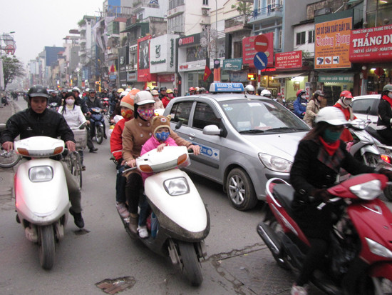 Một phụ huynh đón hai con nhỏ về nhà giữa giờ cao điểm