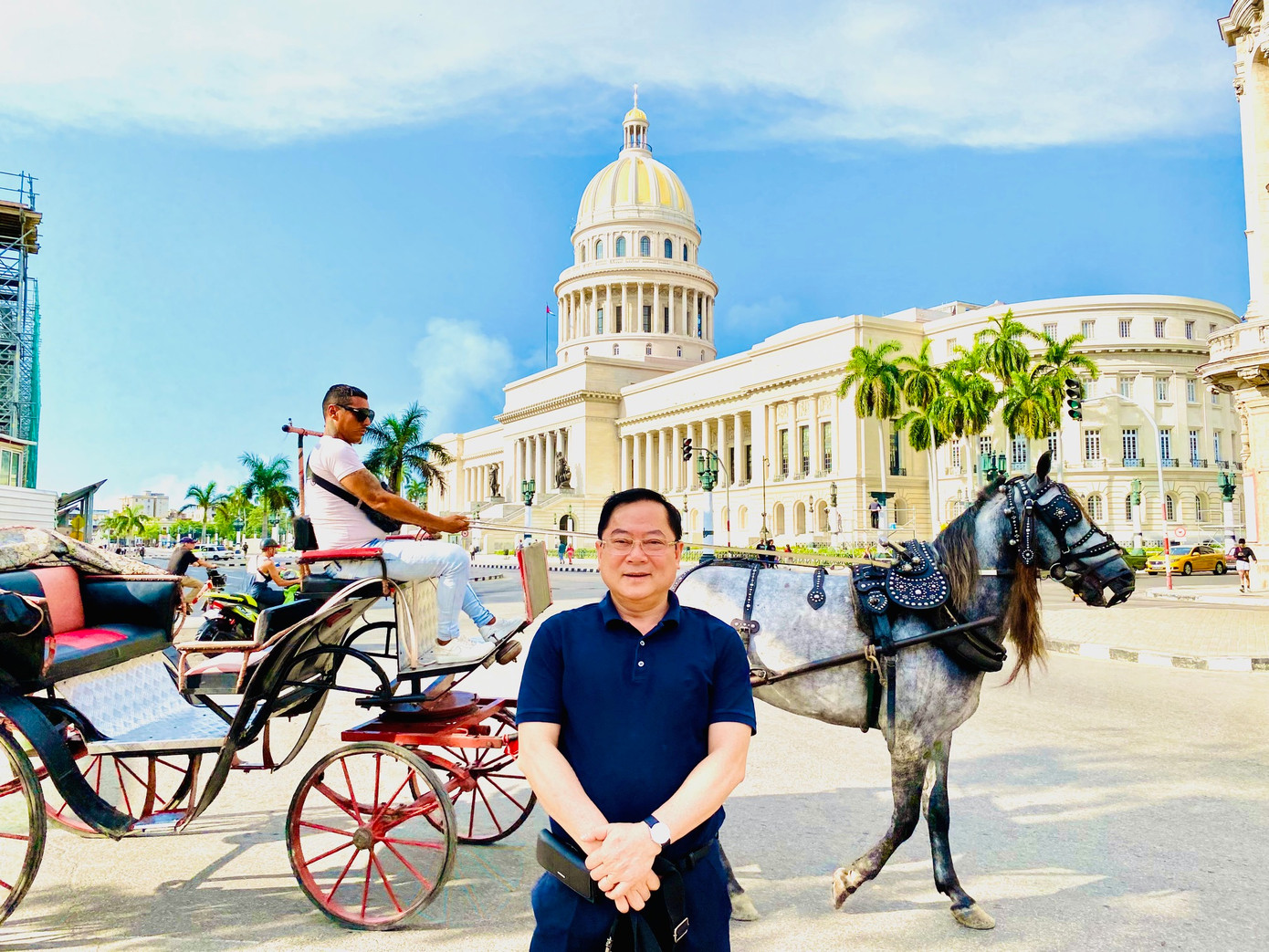 Tác giả trên nền một chiếc xe cổ đi ngang qua toà nhà Capitolio nổi tiếng ở La Habana.