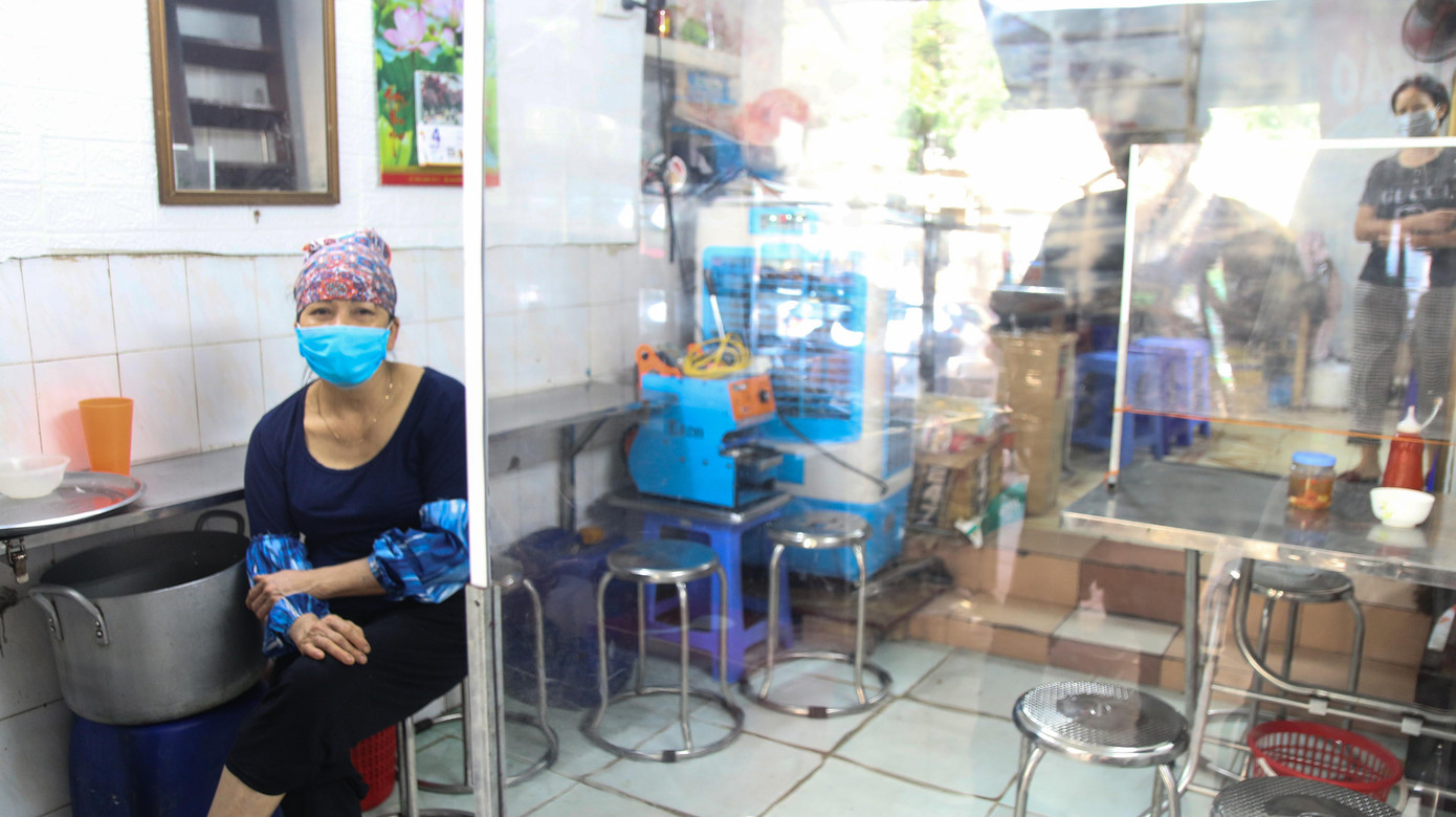 Hàng ăn sáng trên phố Phủ Doãn đìu hiu ngóng khách buổi sáng cuối tuần. Quán dựng vách ngăn, khuyến khích khách mua mang đi, giao hàng tận nơi