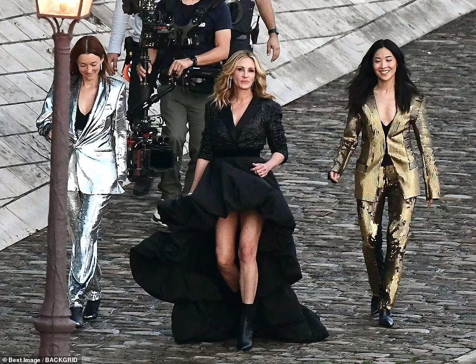 Minh tinh Hollywood mặc chiếc váy đen mullet (chân váy trước ngắn sau dài) bồng bềnh, kết hợp boot đen thấp cổ cao gót.