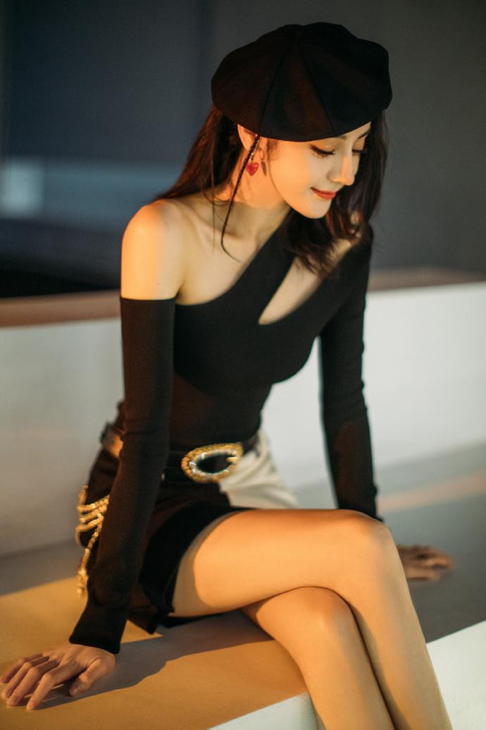 Trong ảnh, Nhiệt Ba mặc áo đen lệch vai bó sát cơ thể và váy zip ngắn đen - trắng, kết hợp boot da chiến binh, mũ nồi. Phụ kiện kèm theo là vòng tay vàng, bông tai hình trái tim đỏ, nhẫn, thắt lưng da và dây xích quanh hông. Tất cả tạo nên tổng thể cá tính, năng động, hiện đại mà cũng rất quyến rũ.