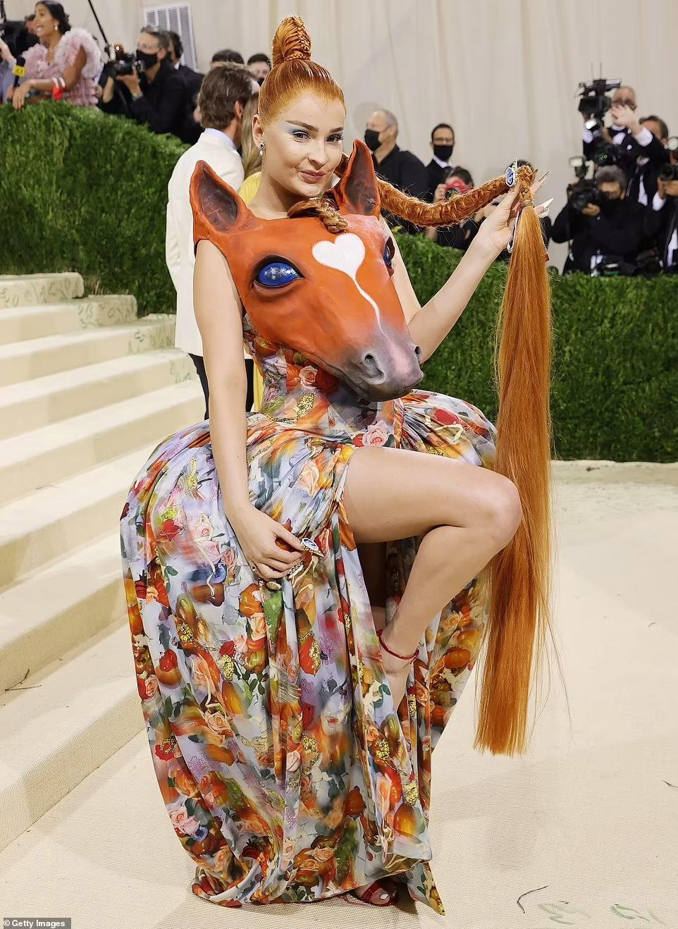 Ca sĩ Kim Petras đeo đầu ngựa trước ngực. Trên đỉnh đầu con ngựa còn có đoạn tóc tết giống với kiểu tóc của mỹ nhân 29 tuổi.