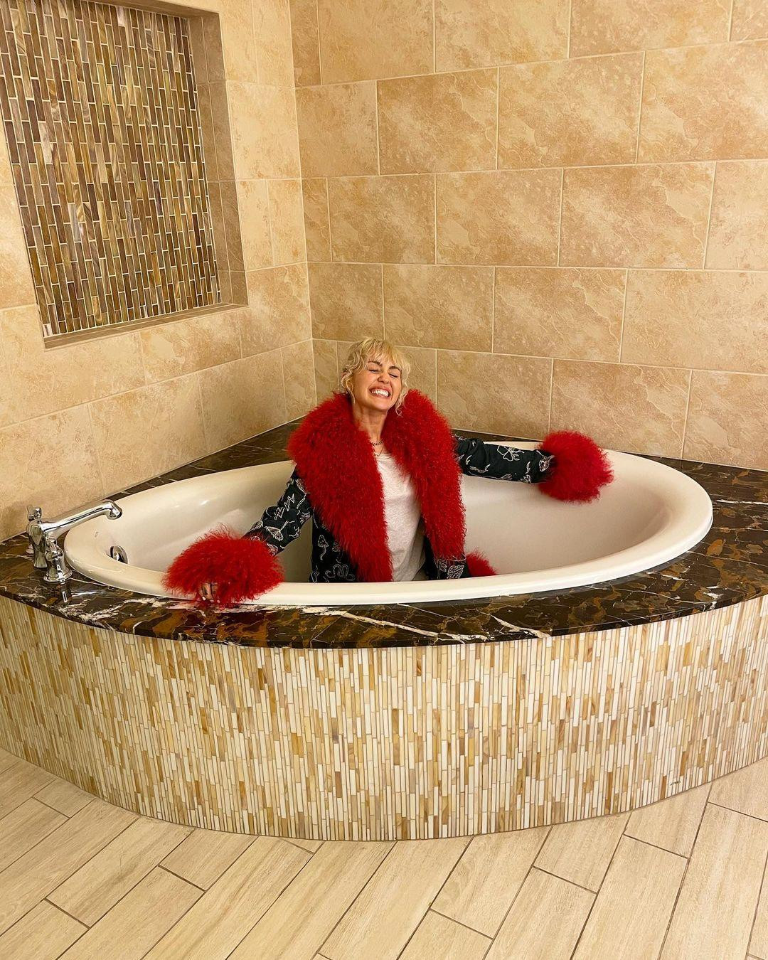 Miley Cyrus mặc áo lông dày trịch cười "thả phanh" trong bồn tắm. Ảnh: Instagram.